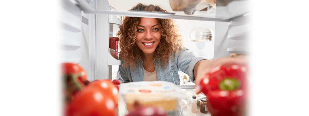 A woman grabbing food out of her fridge