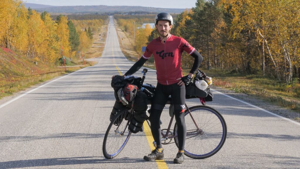 Grn Jersey man posing with bike on nice long road