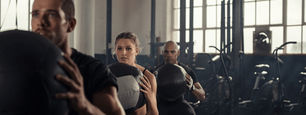 People at the gym holding medicine balls