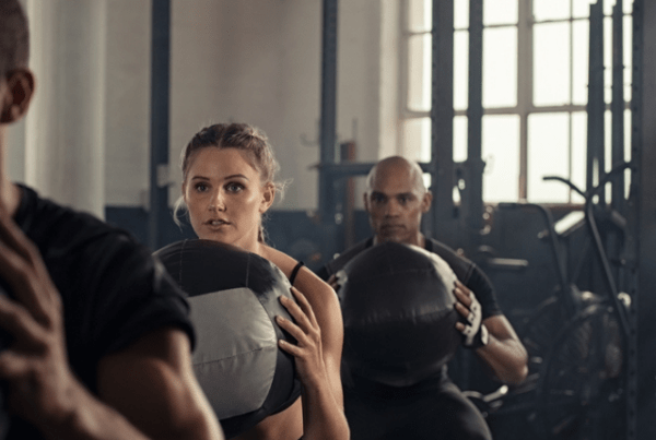 People at the gym holding medicine balls