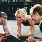 Diverse friends smiling while planking together on a gym floor