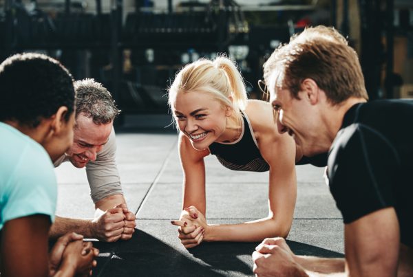 Diverse friends smiling while planking together on a gym floor