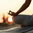 Close-up of woman in lotus position meditating at sunset.