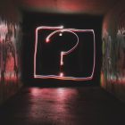 Why use questions over commands - image of a neon question mark at the end of a corridor