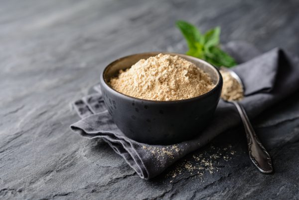 Adaptogens - image of Maca powder in a bowl with a spoon at the side