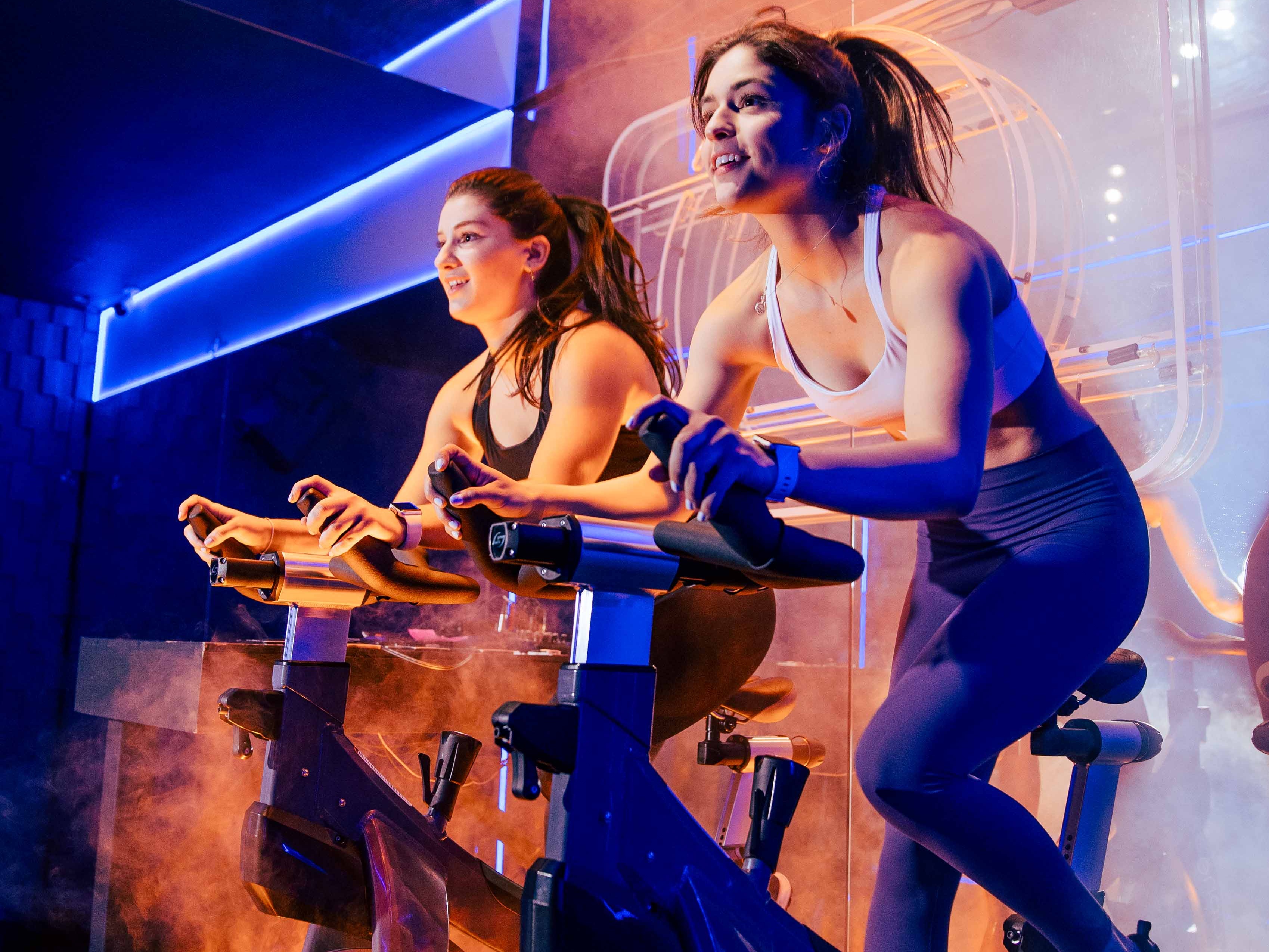 Indoor cycling - image of two people participating in an indoor cycling class