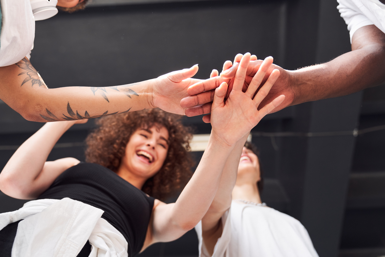 Group Exercise Instructor - image of low angle portrait of smiling people standing after dance classes while holding hands up together and laughing