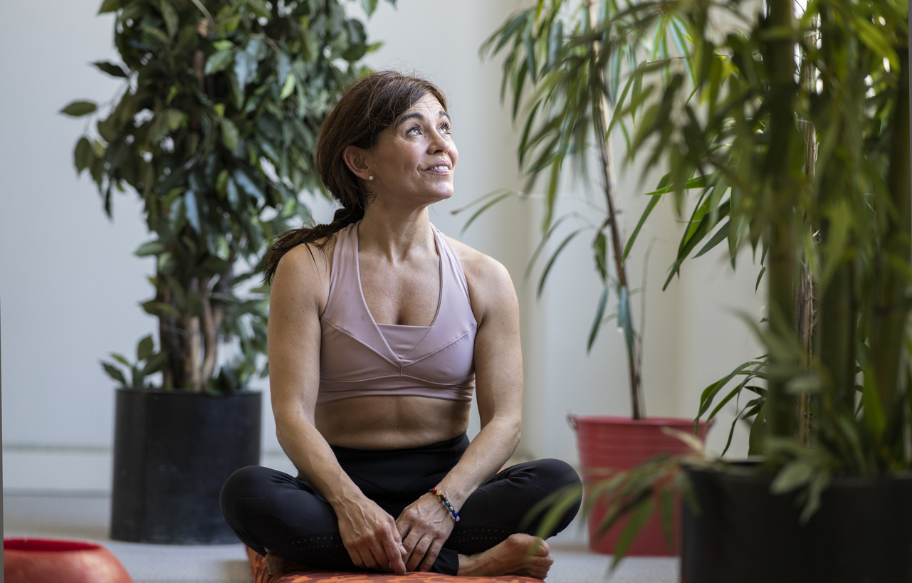 Yoga, meditation and mental health - image of woman sitting relaxed in a yoga room looking out a window