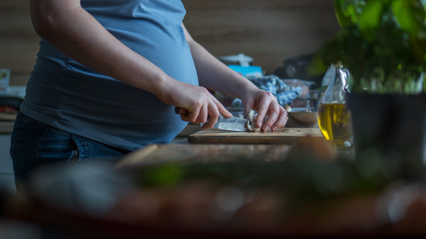 Pregnancy nutrition -Close up image of pregnant woman with knife cutting mushrooms