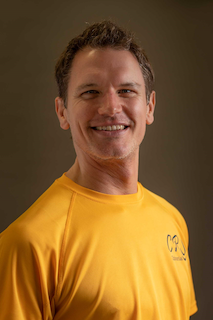 Headshot of Craig Smith smiling wearing a yellow t-shirt.
