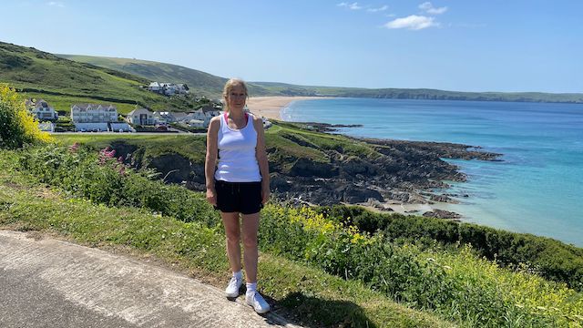 Blue Space - Image of Sarah on a coastal path overlooking a beautiful bay with blue water and a very blue sky.