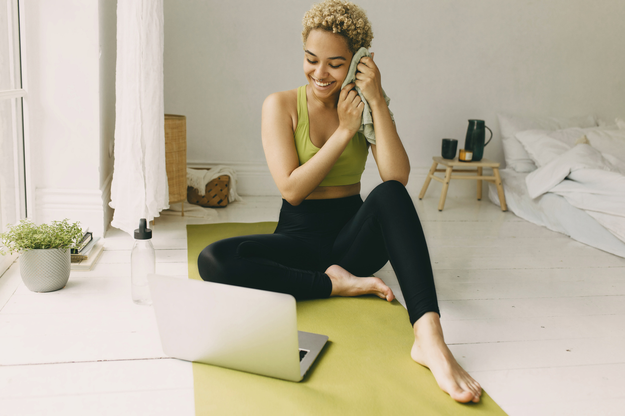 Marketing your group ex offering - image of happy woman looking at her computer having finished teaching a workout