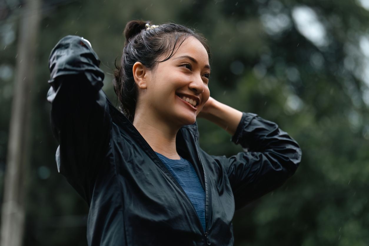 Winter fitness - Image of a woman smiling about to put her hood up as it has started raining