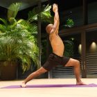 mens role in yoga evolution - Image of a man practising yoga in a studio with a huge indoor plant in the background