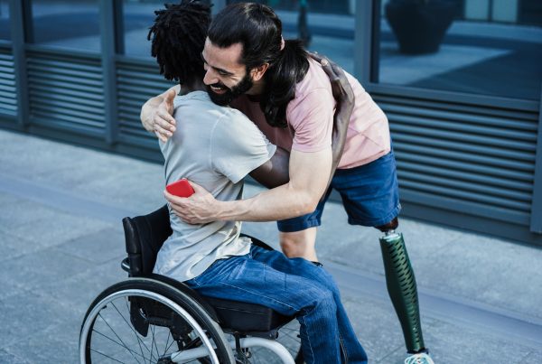 Accessible and inclusive - Image of friends with different disabilities hugging each other outdoors.