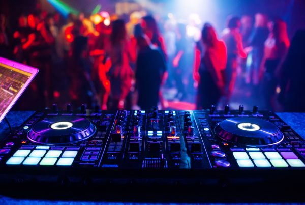 making music for fitness classes - Image of controller DJ mixer in a nightclub at a party against the background of blurred silhouettes of dancing people