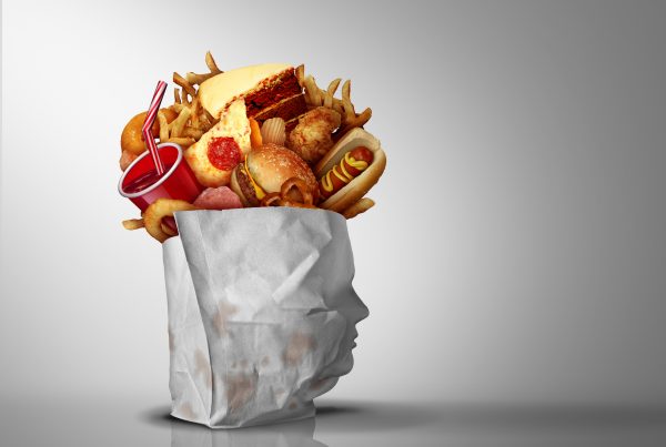 ultra-processed food - this shows a multiude of processed foods in a wrapper that appears in the shape of a person's face. Almost like the ultra-processed food is coming our of their head.