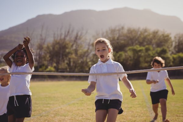 Youth Athletic development - Schoolgirls running toward finishing line during egg and spoon race in park
