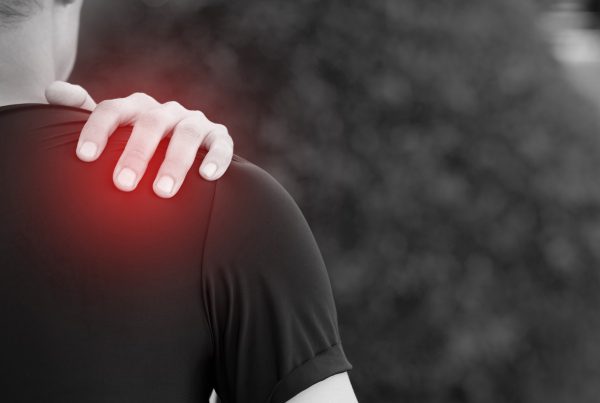 Does your client have frozen shoulder? Image of someone holding their shoulder with pain radiating out from under their hand